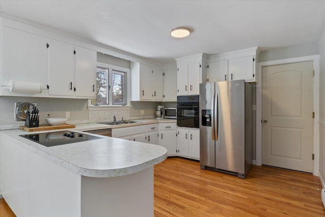 kitchen with sink, white cabinetry, kitchen peninsula, light hardwood / wood-style floors, and black appliances