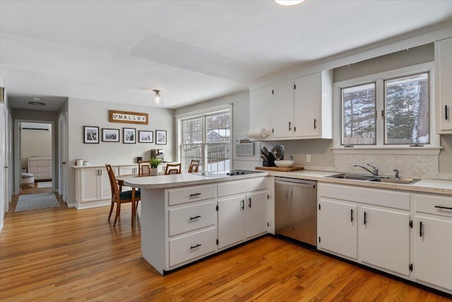 kitchen featuring stainless steel dishwasher, kitchen peninsula, sink, and white cabinets