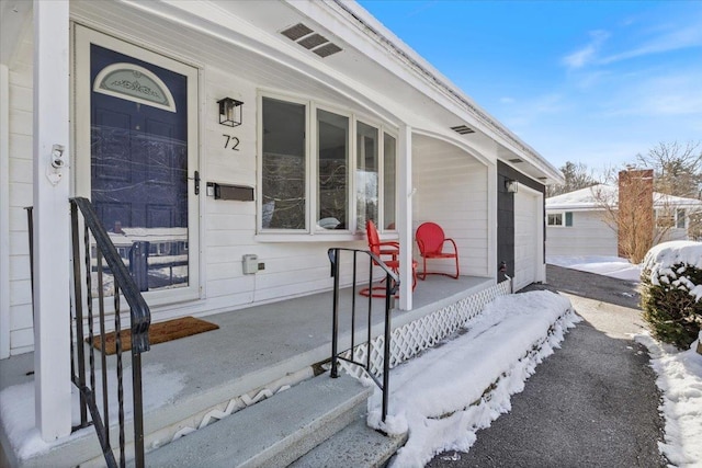 snow covered property entrance with covered porch