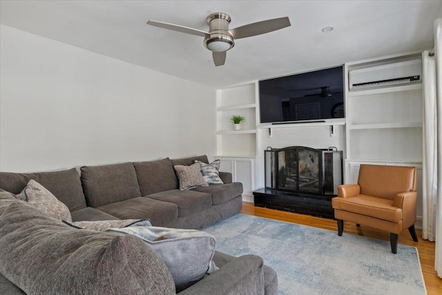 living room with ceiling fan, a wall mounted air conditioner, and light hardwood / wood-style floors