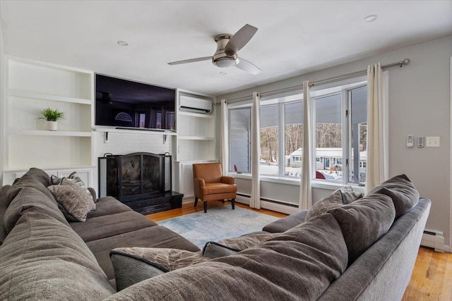 living room featuring an AC wall unit, a fireplace, ceiling fan, baseboard heating, and light hardwood / wood-style flooring