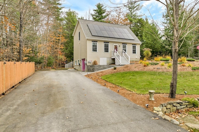 view of front of home with a front yard and solar panels