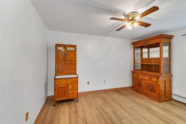 spare room featuring a baseboard heating unit, light hardwood / wood-style floors, and ceiling fan