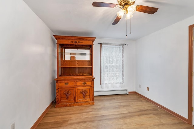 spare room featuring light wood-type flooring, ceiling fan, and baseboard heating