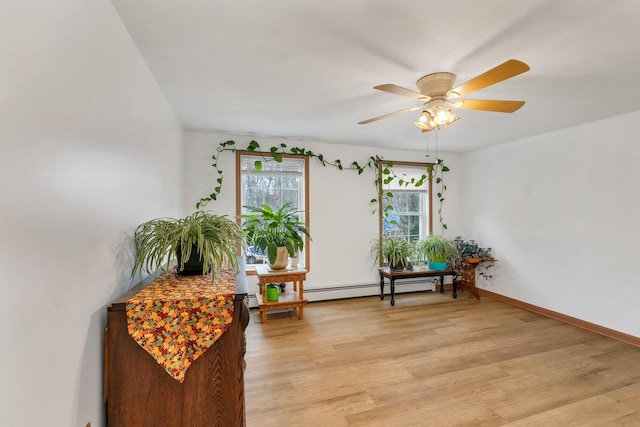 sitting room with a baseboard heating unit, light hardwood / wood-style flooring, and ceiling fan