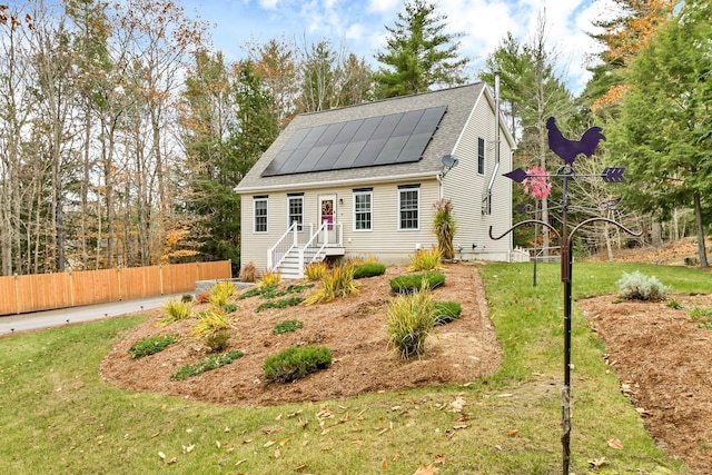 view of front of property featuring a front lawn and solar panels