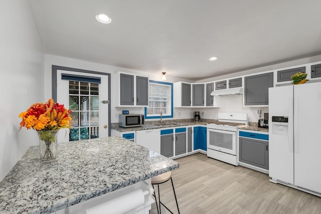 kitchen featuring gray cabinetry, white appliances, kitchen peninsula, and a kitchen bar