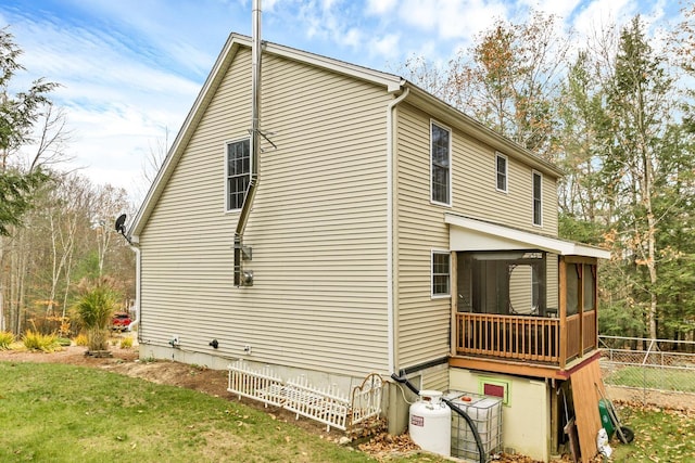 view of side of home featuring a sunroom and a lawn