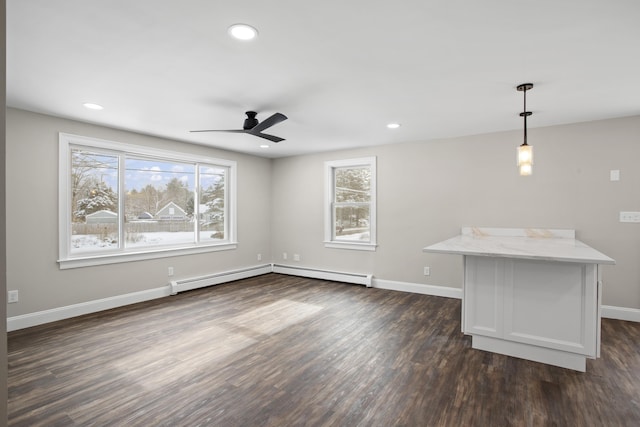 unfurnished living room featuring ceiling fan, plenty of natural light, dark hardwood / wood-style floors, and baseboard heating