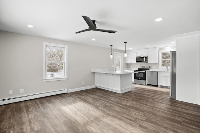 kitchen featuring pendant lighting, white cabinetry, stainless steel appliances, dark hardwood / wood-style flooring, and kitchen peninsula