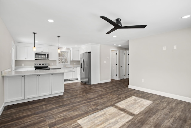 kitchen featuring hanging light fixtures, white cabinetry, appliances with stainless steel finishes, and dark hardwood / wood-style floors