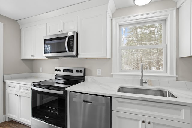 kitchen with light stone countertops, appliances with stainless steel finishes, sink, and white cabinets