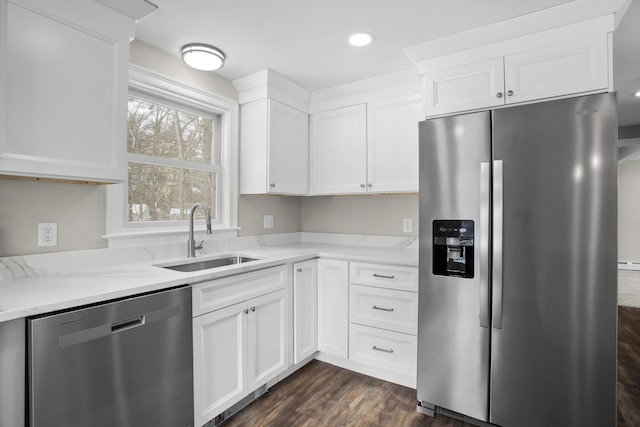 kitchen with dark wood-type flooring, sink, appliances with stainless steel finishes, light stone countertops, and white cabinets