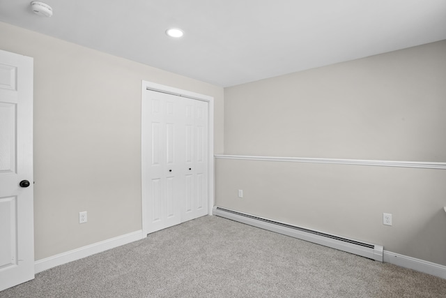 unfurnished bedroom featuring light colored carpet, a closet, and baseboard heating