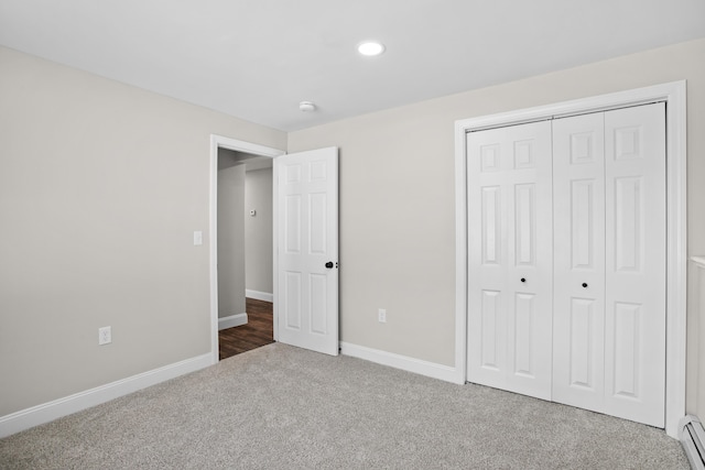 unfurnished bedroom with a baseboard radiator, a closet, and carpet flooring