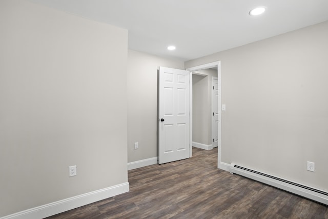 empty room with dark hardwood / wood-style floors and baseboard heating