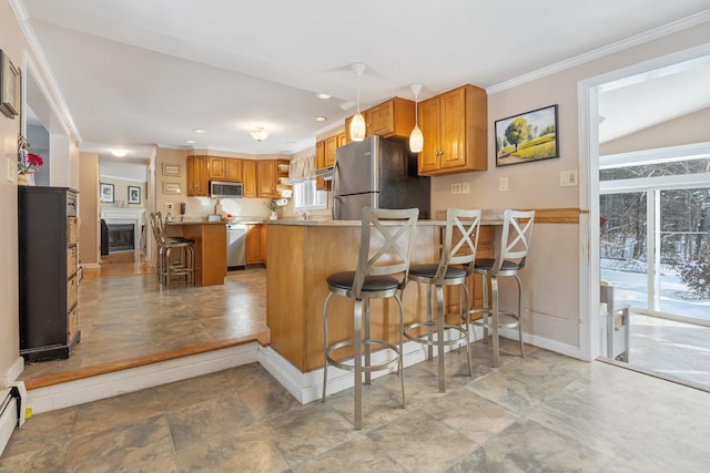 kitchen featuring hanging light fixtures, stainless steel appliances, ornamental molding, a kitchen bar, and kitchen peninsula