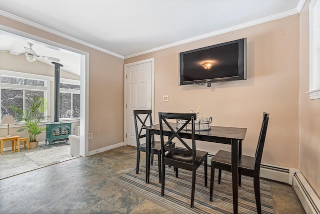 dining room with baseboard heating, ceiling fan, ornamental molding, and a wood stove