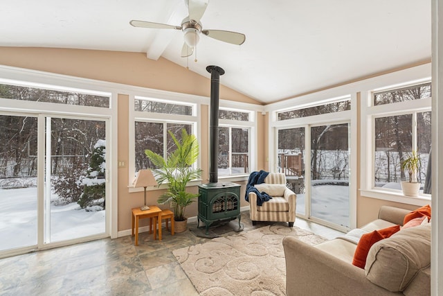 sunroom with vaulted ceiling with beams, ceiling fan, and a wood stove