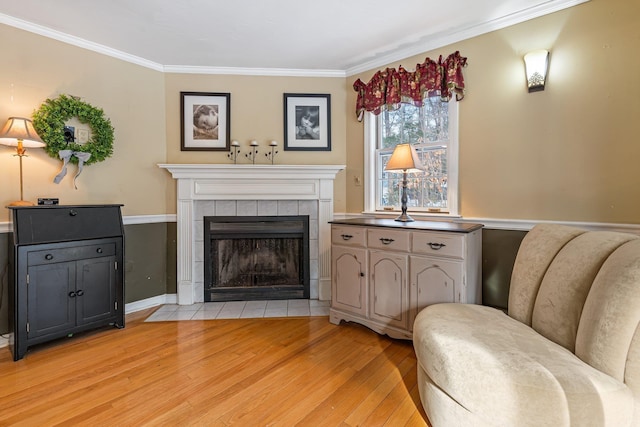 living area with crown molding, a tile fireplace, and light wood-type flooring