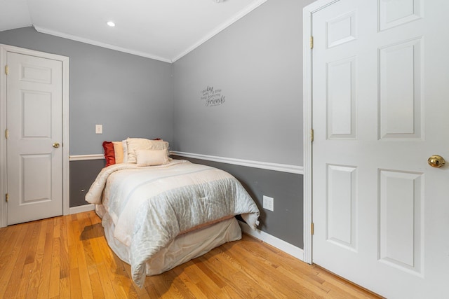 bedroom with crown molding, lofted ceiling, and light hardwood / wood-style flooring