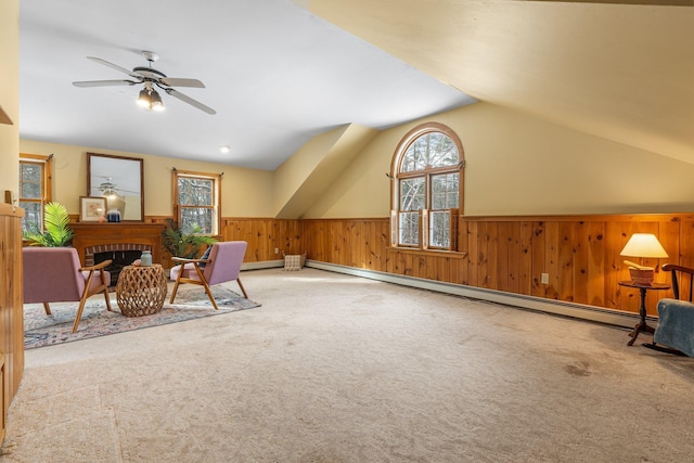 sitting room featuring lofted ceiling, wood walls, a brick fireplace, baseboard heating, and carpet