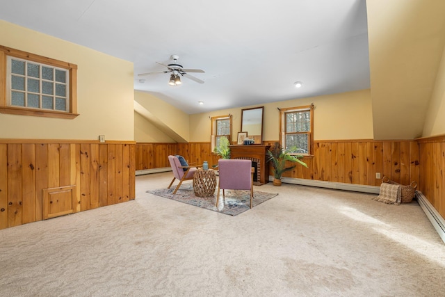 dining space with ceiling fan, wood walls, baseboard heating, and carpet flooring