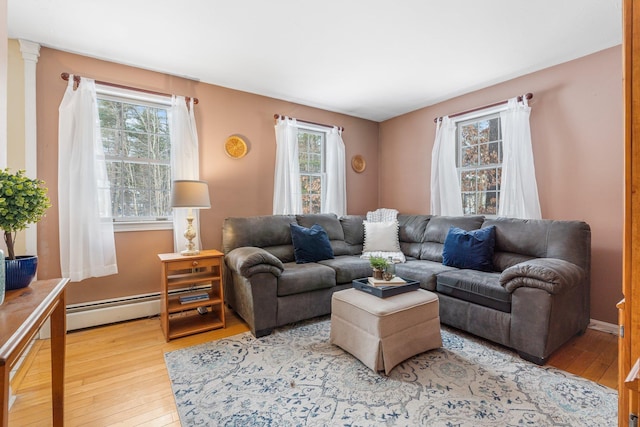 living room with wood-type flooring, baseboard heating, and plenty of natural light