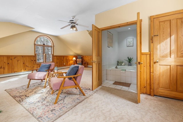 living area featuring ceiling fan, lofted ceiling, light carpet, and wooden walls