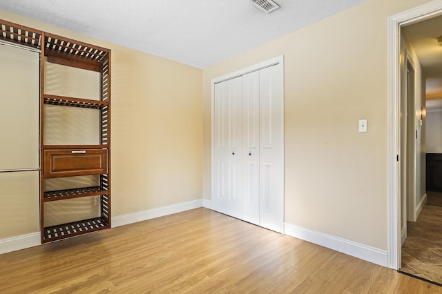 unfurnished bedroom featuring light hardwood / wood-style floors, a closet, and a textured ceiling