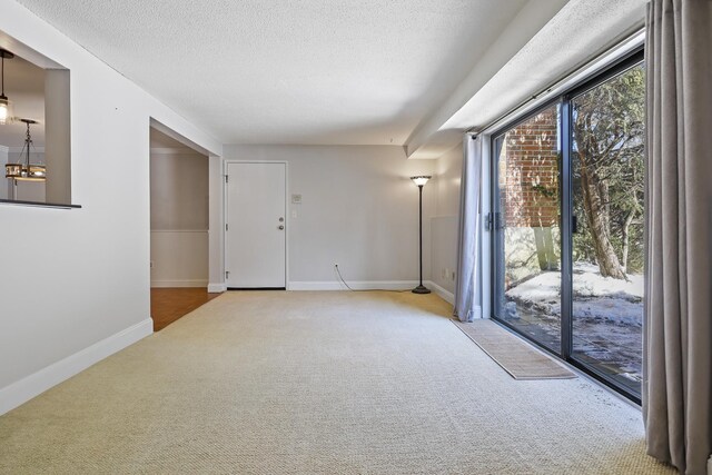 carpeted spare room featuring an inviting chandelier and a textured ceiling