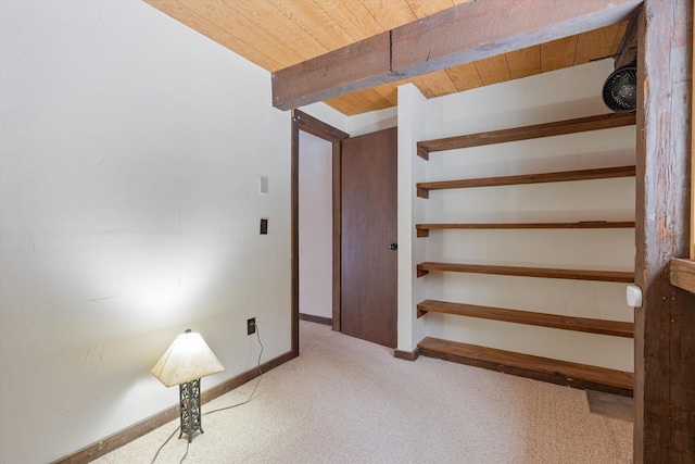 stairway with beam ceiling, wooden ceiling, and carpet