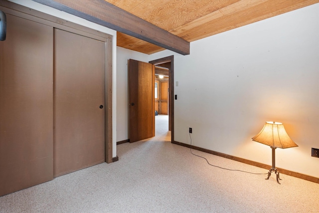 unfurnished bedroom with beamed ceiling, wooden ceiling, and a closet