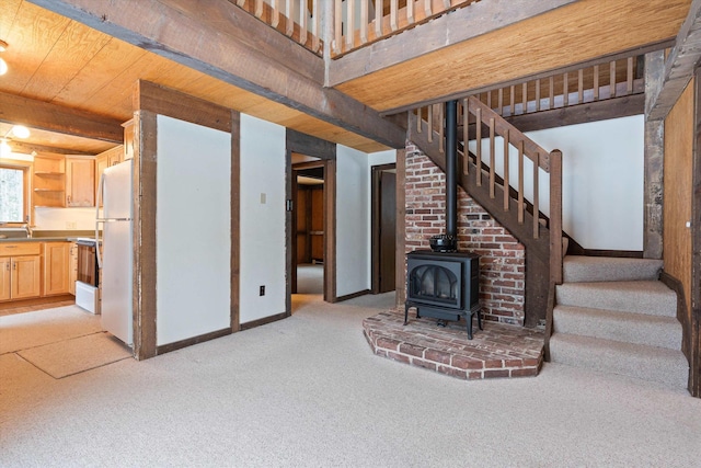 unfurnished living room with a wood stove, light colored carpet, and wooden ceiling