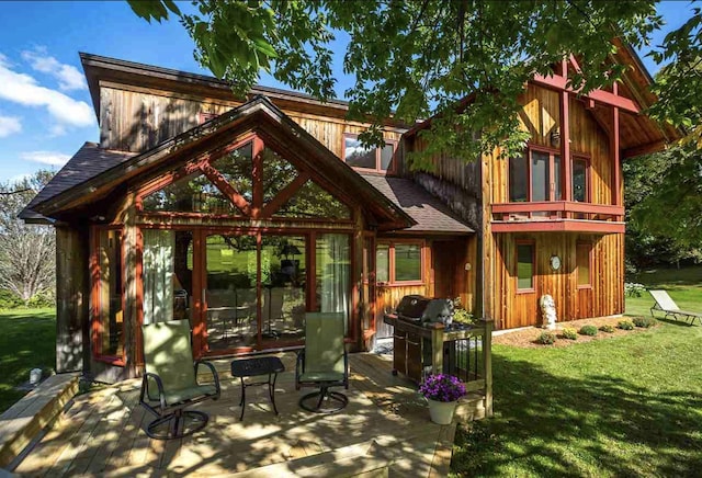 rear view of house with a wooden deck, a yard, and a sunroom