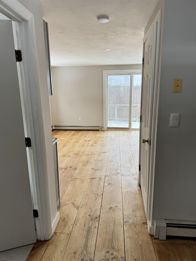 corridor with light hardwood / wood-style floors and a baseboard heating unit