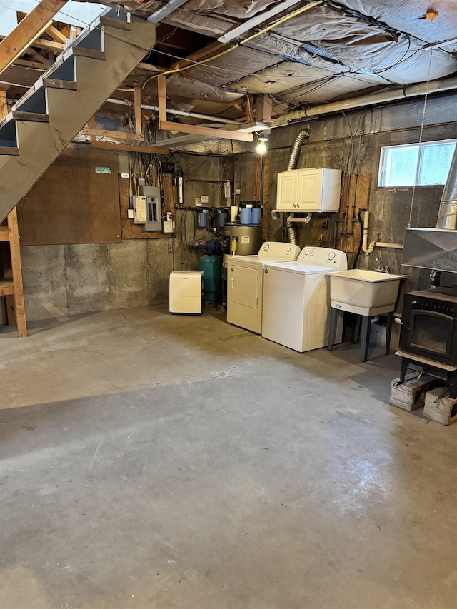 basement with washing machine and dryer, sink, a wood stove, and electric panel