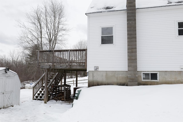 snow covered property with a deck and a shed