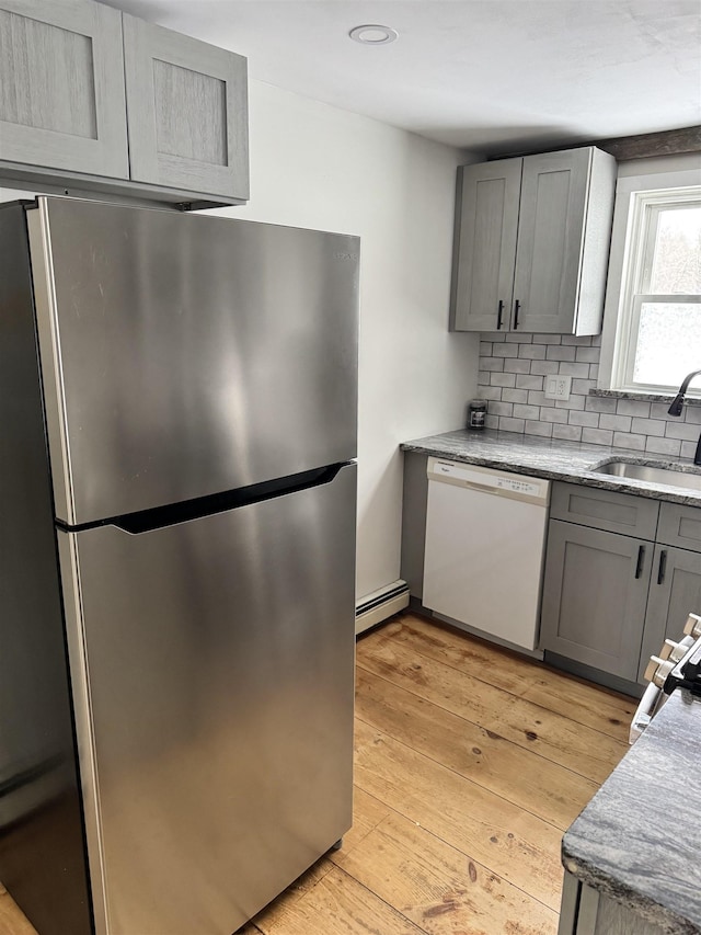 kitchen featuring sink, stainless steel refrigerator, baseboard heating, gray cabinetry, and white dishwasher