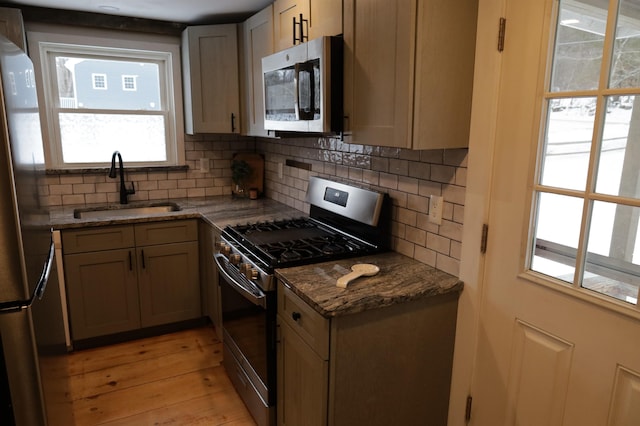 kitchen featuring sink, decorative backsplash, stainless steel appliances, and dark stone counters