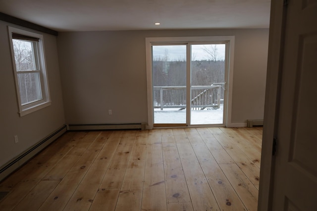 empty room featuring a baseboard radiator and light hardwood / wood-style floors