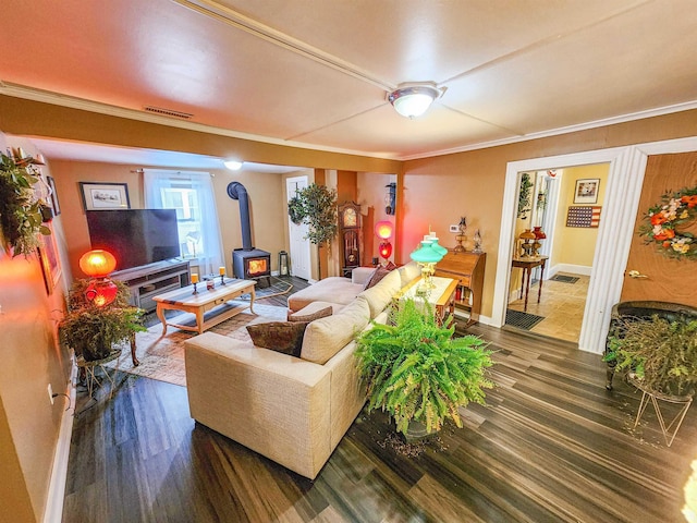 living room with crown molding, dark hardwood / wood-style floors, and a wood stove