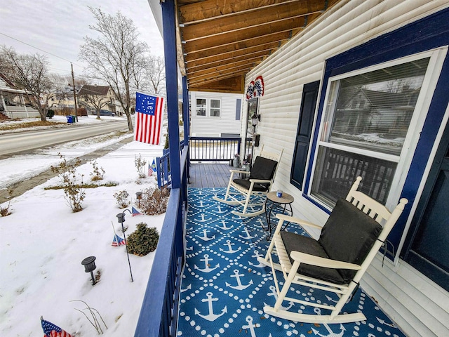 snow covered deck featuring covered porch