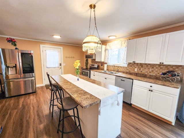 kitchen with white cabinetry, stainless steel appliances, sink, and pendant lighting