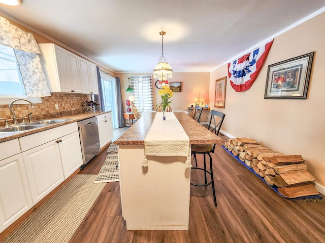 kitchen with a breakfast bar area, dishwasher, white cabinets, a kitchen island, and decorative light fixtures