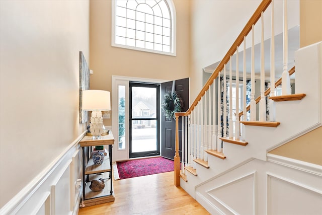 entryway with a towering ceiling and light hardwood / wood-style flooring