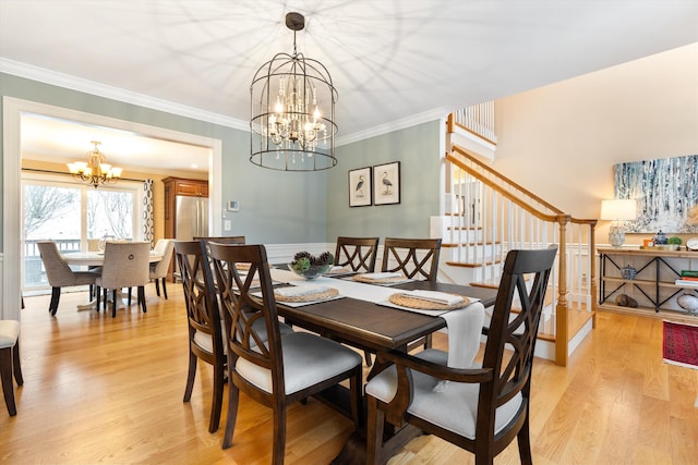 dining space with crown molding, a chandelier, and light hardwood / wood-style flooring