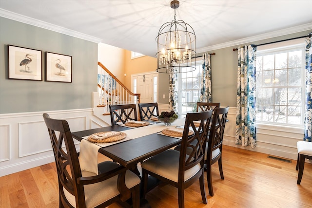 dining area featuring crown molding, an inviting chandelier, and light wood-type flooring