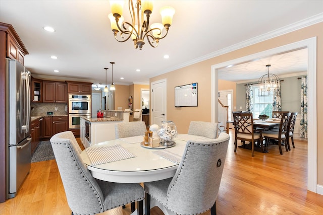 dining room with ornamental molding, a chandelier, and light hardwood / wood-style flooring