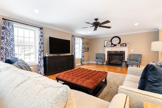 living room with crown molding, ceiling fan, a fireplace, and light hardwood / wood-style flooring